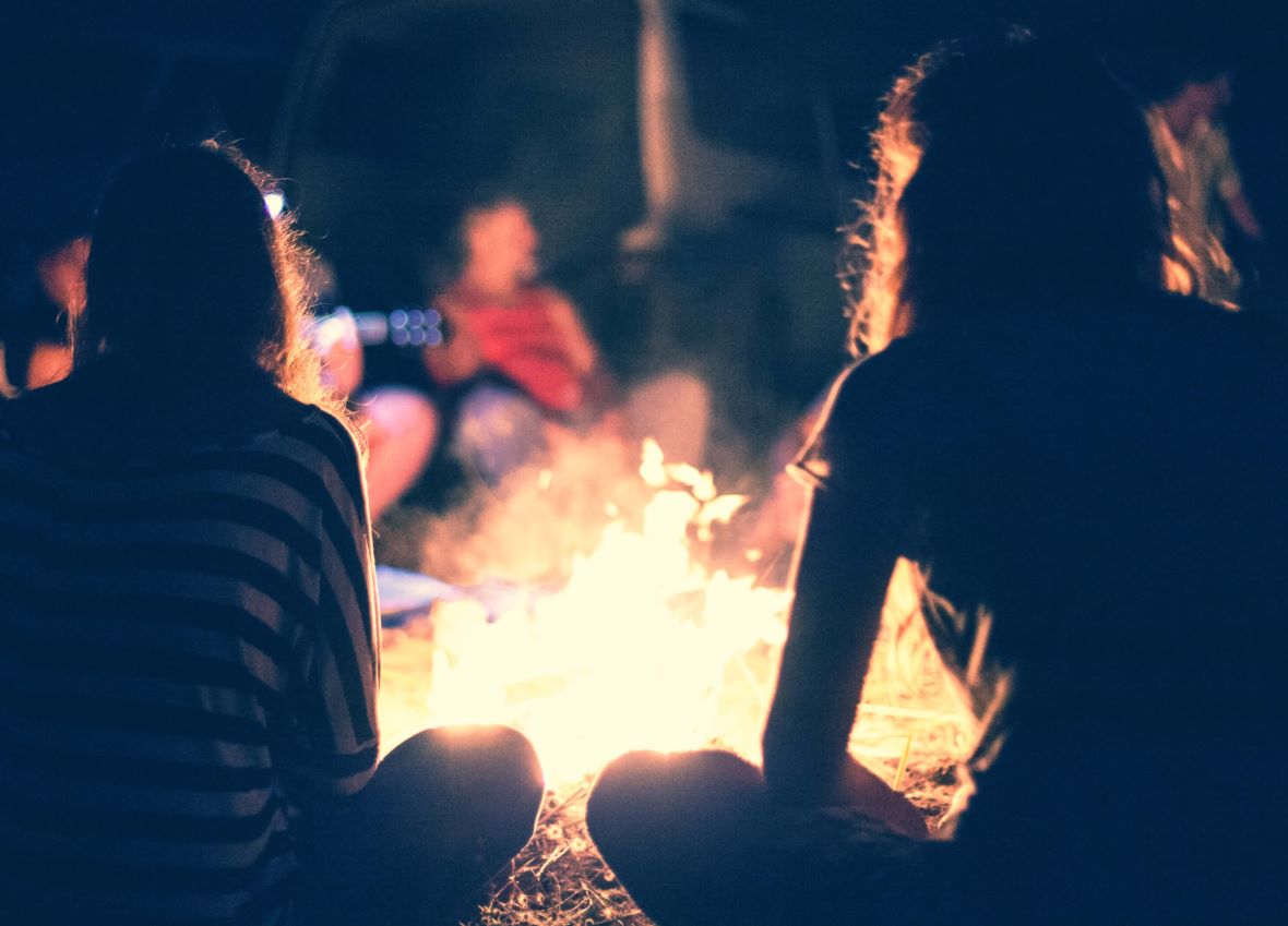 People sit at night round a bright bonfire